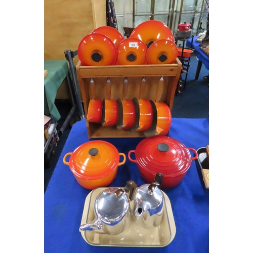 A Le Creuset wooden pot stand with graduating saucepans and lids