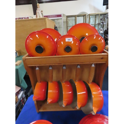 A Le Creuset wooden pot stand with graduating saucepans and lids