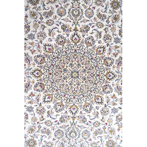 2004 - AN IVORY GROUND FINE PILE HAND WOVEN KESHAN RUG with sunburst central medallion on floral/foliate pa... 