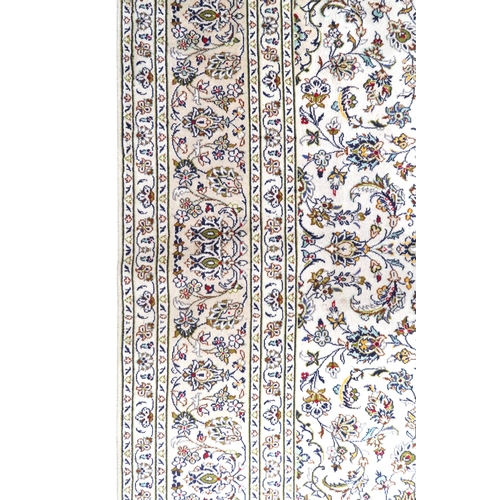 2004 - AN IVORY GROUND FINE PILE HAND WOVEN KESHAN RUG with sunburst central medallion on floral/foliate pa... 