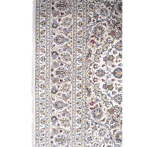 2004 - AN IVORY GROUND FINE PILE HAND WOVEN KESHAN RUG with sunburst central medallion on floral/foliate pa... 