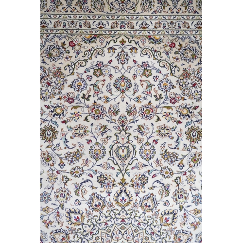 2004 - AN IVORY GROUND FINE PILE HAND WOVEN KESHAN RUG with sunburst central medallion on floral/foliate pa... 