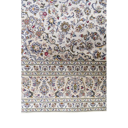 2004 - AN IVORY GROUND FINE PILE HAND WOVEN KESHAN RUG with sunburst central medallion on floral/foliate pa... 