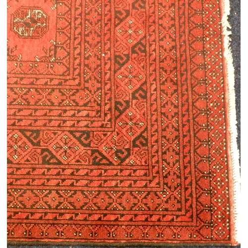 3 - A large red ground Afghan Tekke style rug with distinctive all over lozenge design within multiple d... 