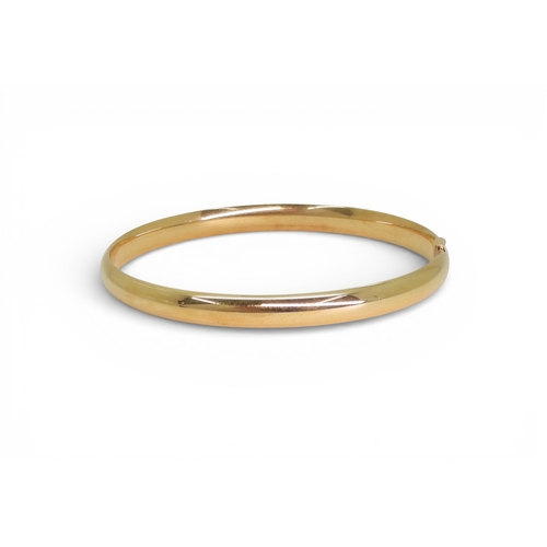 2751 - A CLASSIC PLAIN GOLD BANGLEmade in 14k gold, with gentle domed interior and exterior, the tongue of ... 
