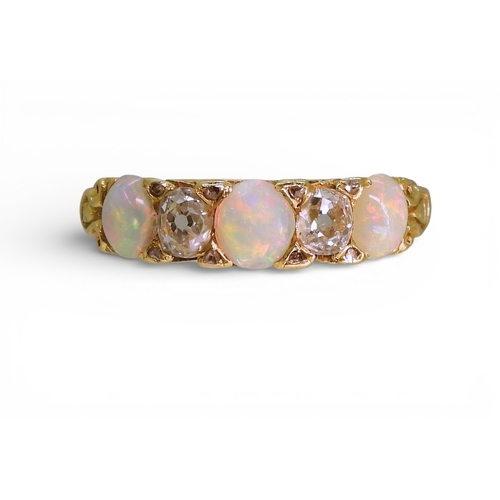 2733 - AN OPAL & DIAMOND RINGin a bright yellow metal decorative scroll mount. Lively opals interspaced... 