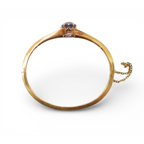 2755 - A SAPPHIRE BANGLEmade in bright yellow metal, and set with a cushion cut natural sapphire of approx ... 