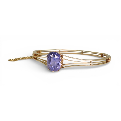 2755 - A SAPPHIRE BANGLEmade in bright yellow metal, and set with a cushion cut natural sapphire of approx ... 