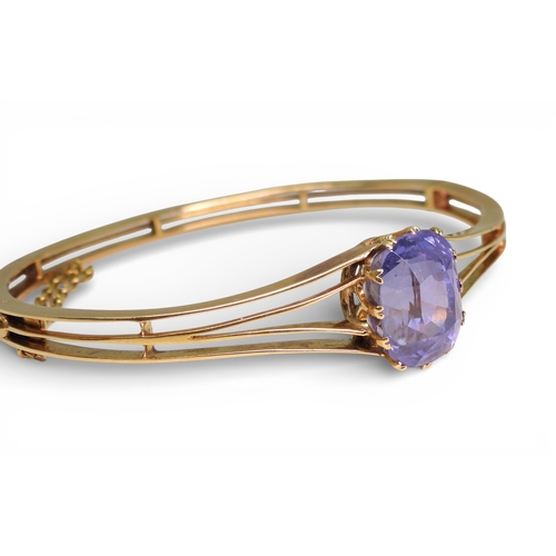 2755 - A SAPPHIRE BANGLEmade in bright yellow metal, and set with a cushion cut natural sapphire of approx ... 