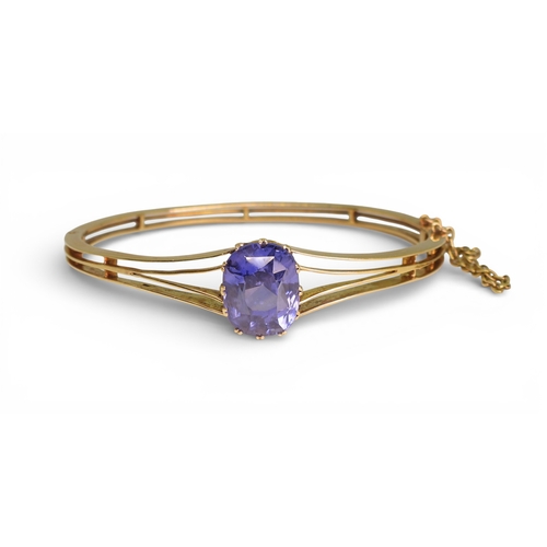 2755 - A SAPPHIRE BANGLEmade in bright yellow metal, and set with a cushion cut natural sapphire of approx ... 
