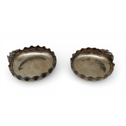 908 - A pair of 900 standard silver dishes, with shaped rims, with cast decoration depicting a pair of bir... 