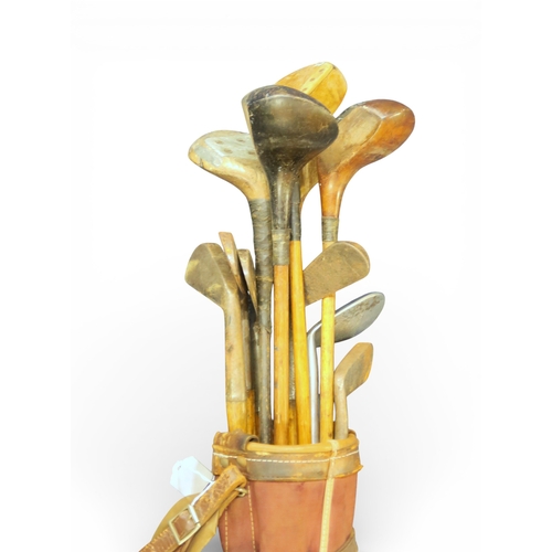 538 - An early-20th century canvas and leather golf bag, containing a selection of hickory shafted clubs, ... 