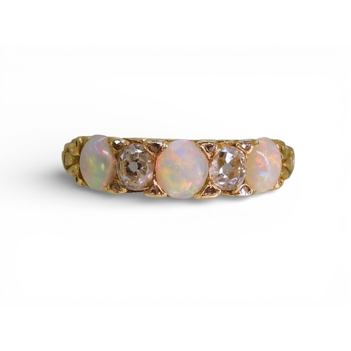 2733 - AN OPAL & DIAMOND RINGin a bright yellow metal decorative scroll mount. Lively opals interspaced... 