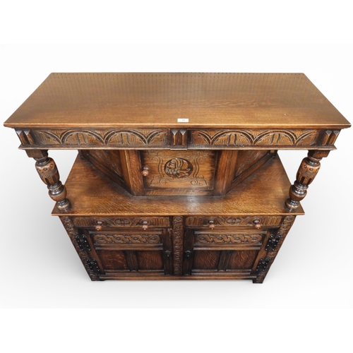 10 - A 20th century oak court cabinet with single carved door flanked by turned columns over pair of draw... 