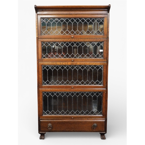An early 20th century oak four tier sectional bookcase with four leaded glazed fall front doors over single drawer on paw feet, 168cm high x 88cm wide x 36cm deep