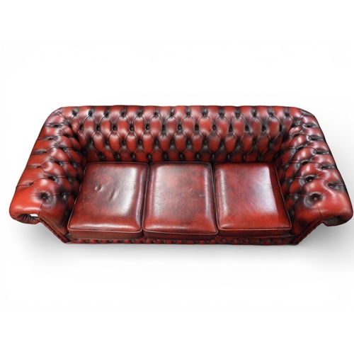 25 - A 20th century Oxblood upholstered Chesterfield style club settee with button upholstered rolled bac... 