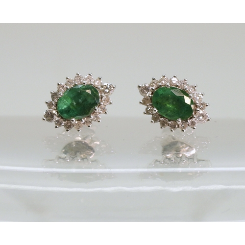 702 - A pair of 18ct white gold emerald and diamond cluster earrings, set with brilliant cut diamonds and ...