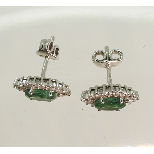 702 - A pair of 18ct white gold emerald and diamond cluster earrings, set with brilliant cut diamonds and ...