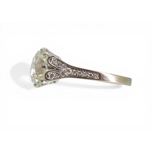 2734 - A SUBSTANTIAL CUSHION CUT DIAMOND RINGre-set in a modern white metal mount, with pave set diamond sh... 