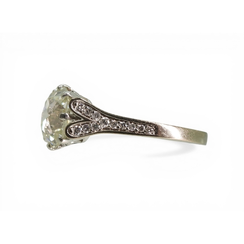 2734 - A SUBSTANTIAL CUSHION CUT DIAMOND RINGre-set in a modern white metal mount, with pave set diamond sh... 