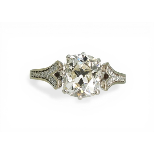 2734 - A SUBSTANTIAL CUSHION CUT DIAMOND RINGre-set in a modern white metal mount, with pave set diamond sh... 
