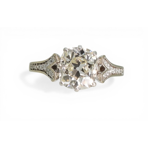 2734 - A SUBSTANTIAL CUSHION CUT DIAMOND RINGre-set in a modern white metal mount, with pave set diamond sh... 
