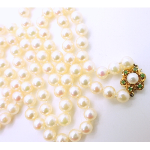 2737 - A MATINEE STRING OF PEARLSthe pearls are cream with a good pink/green lustre, with a 9ct gold, emera... 