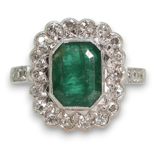 794 - An 18ct white gold emerald and diamond cluster ring, set with a step cut emerald of approx 9mm x 7mm... 
