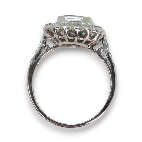 794 - An 18ct white gold emerald and diamond cluster ring, set with a step cut emerald of approx 9mm x 7mm... 