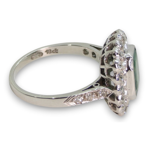 794 - An 18ct white gold emerald and diamond cluster ring, set with a step cut emerald of approx 9mm x 7mm... 