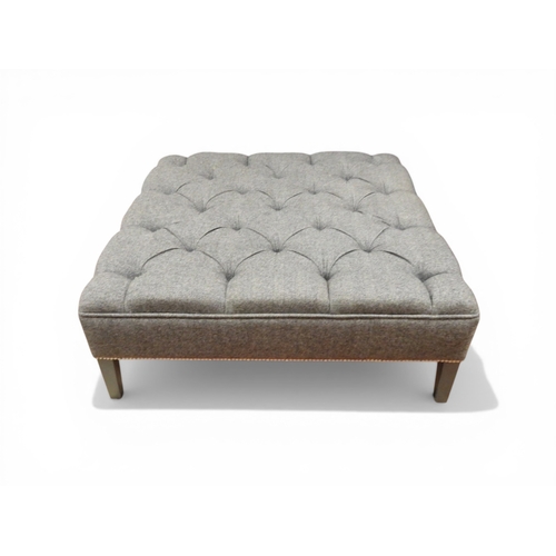 A large contemporary gray button upholstered ottoman/footstool with studded bottom edge on gray square tapering supports, 37cm high x 101cm wide x 101cm deep