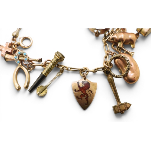 712 - A yellow metal charm bracelet, with twelve 9ct gold charms, seven yellow metal charms, to include a ... 