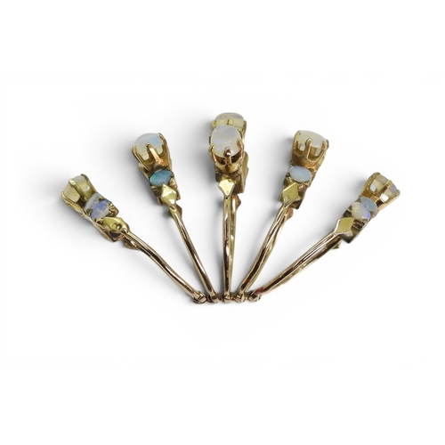 717 - A bright yellow metal five strand ring, each set with opals, size N1/2, weight 5.8gms