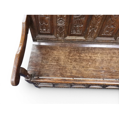 2034 - A 17TH/18TH CENTURY OAK SIX PANEL BACKED SETTLEpanelled back carved with king and men at arms surmou... 