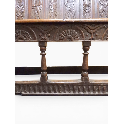 2034 - A 17TH/18TH CENTURY OAK SIX PANEL BACKED SETTLEpanelled back carved with king and men at arms surmou... 