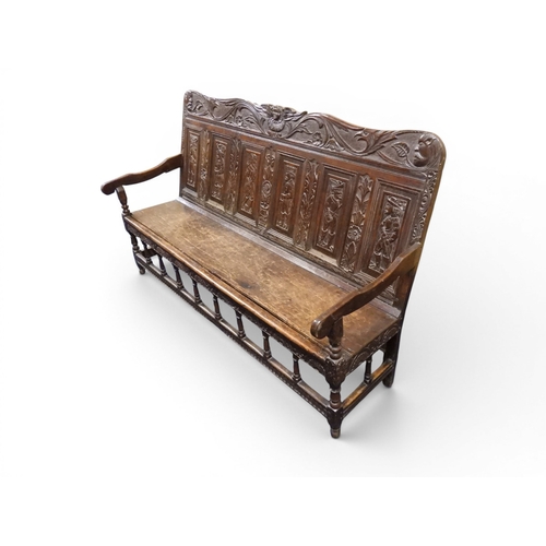 2034 - A 17TH/18TH CENTURY OAK SIX PANEL BACKED SETTLEpanelled back carved with king and men at arms surmou... 