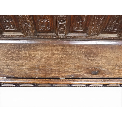 2034 - A 17TH/18TH CENTURY OAK SIX PANEL BACKED SETTLEpanelled back carved with king and men at arms surmou... 