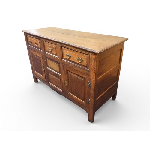 2035 - AN 18TH CENTURY OAK KITCHEN DRESSER BASEwith three plank top over three short drawers and panel cabi... 