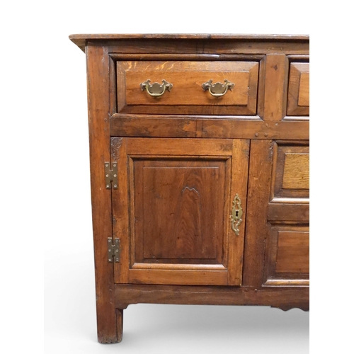2035 - AN 18TH CENTURY OAK KITCHEN DRESSER BASEwith three plank top over three short drawers and panel cabi... 