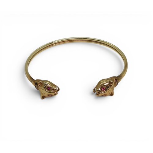 2756 - A LEOPARD BANGLEmade in 9ct gold and set with ruby eyes and collars. Inner diameter 6.2cm, weight 11... 