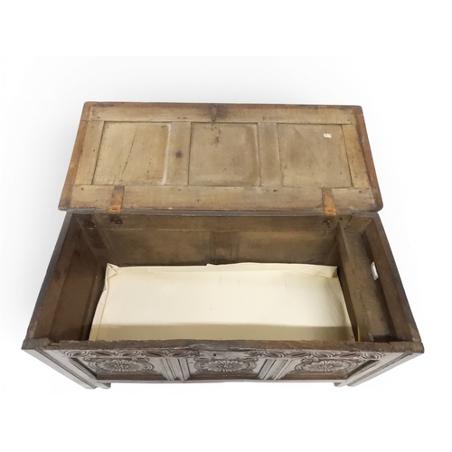 2022 - A 17TH/18TH CENTURY OAK BLANKET CHESTwith three panel lid with wrought iron fitting over carved thre... 