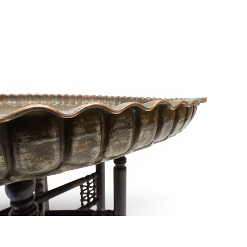 2023 - A 19TH/20TH CENTURY MOORISH COPPER TRAY TOP FOLDING TABLEcircular copper top with raised gallery edg... 
