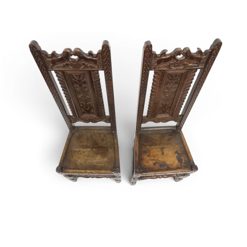 2031 - A PAIR OF 17TH CENTURY STYLE OAK HALL CHAIRS with floral carved panel backs surmounted with twinned ... 