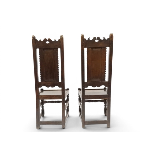 2031 - A PAIR OF 17TH CENTURY STYLE OAK HALL CHAIRS with floral carved panel backs surmounted with twinned ... 