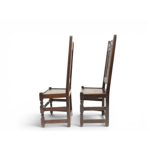 2031 - A PAIR OF 17TH CENTURY STYLE OAK HALL CHAIRS with floral carved panel backs surmounted with twinned ... 