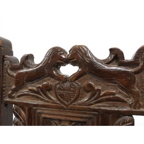 2031 - A PAIR OF 17TH CENTURY STYLE OAK HALL CHAIRS with floral carved panel backs surmounted with twinned ... 