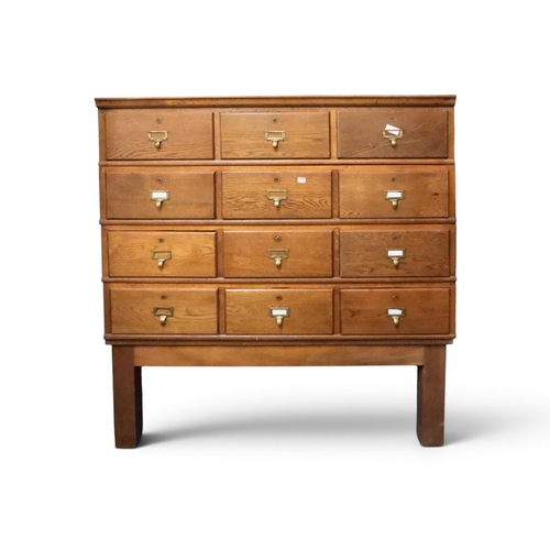 25 - An early 20th century oak index card chest with four rows of three index drawer with brass drawer pu...