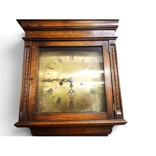 27 - An early 20th century oak cased Ingersoll longcase clock with brass dial bearing Arabic and Roman nu...