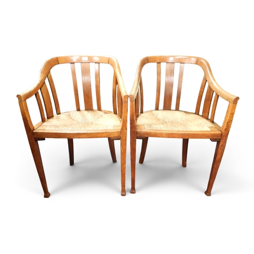 3 - A pair of early 20th century oak framed Arts & Crafts style horseshoe backed armchairs with rush...
