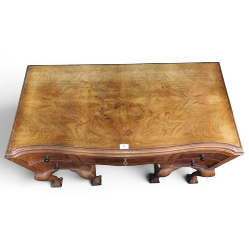 16 - An early 20th century mahogany veneered serpentine front writing desk with long central drawer flank... 